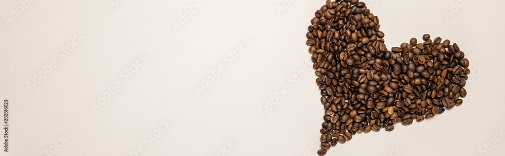 top view of heart made of coffee grains on beige background, panoramic shot top view of heart made of coffee grains on beige background, panoramic shot