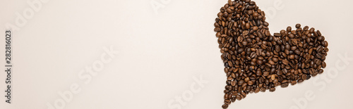 top view of heart made of coffee grains on beige background, panoramic shot