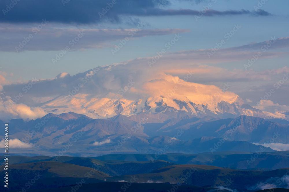 Elbrus at sunset is covered with a hat of clouds. Elbrus at sunset.