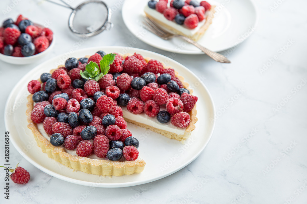 blueberry and raspberry tart on white marble background blueberry and raspberry tart on white marble background