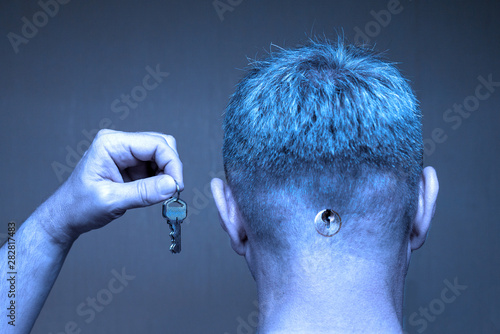 Billede på lærred A man with a keyhole in the back of his head holds keys in a raised hand