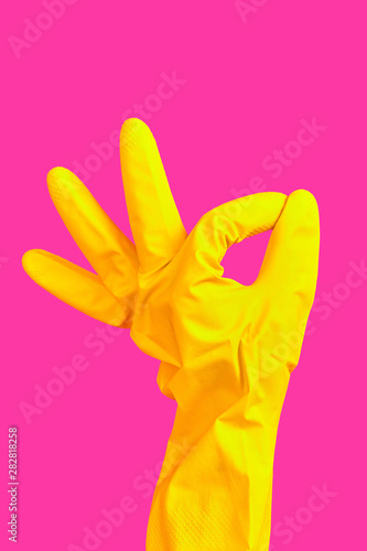 Hand gesture OK in yellow rubber glove isolated on pink background. cleaner hand shows OK gesture. Minimalism poster concpet. Copy space