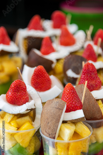 Colorful inviting and refreshing cups of fruit salad with fresh strawberries, coconut, pineapple and kiwi photo