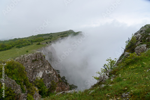 heavy fog in the mountains after the rain with growing trees on the slope of a barely visible sea. Spring view of the Crimea.