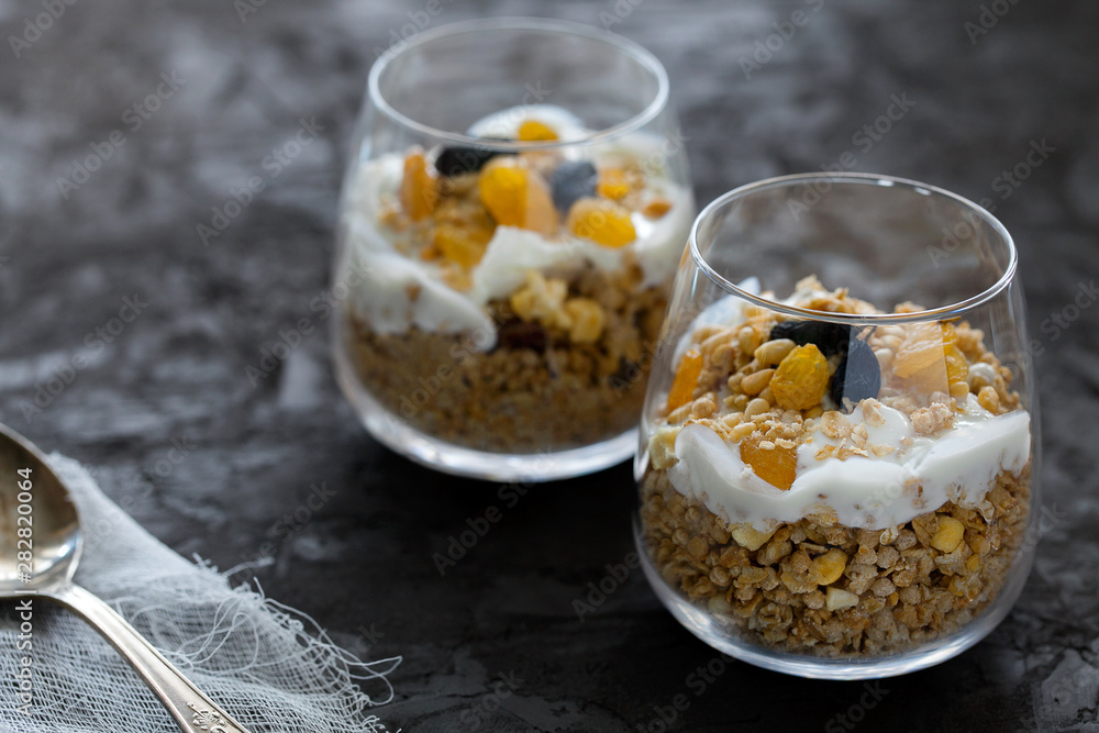 Φωτογραφία Glass of homemade oat granola or muesli with natural greek yogurt or buttermilk,raisins and nuts on dark gray textured background copy space