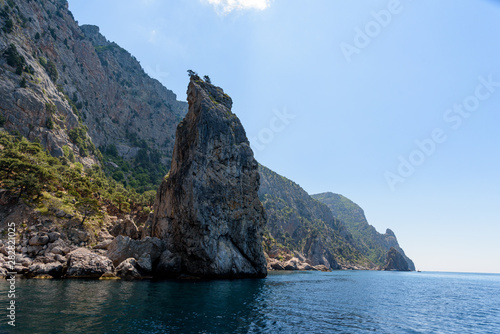 cliff shore from the side of a pleasure boat in the black sea  on a sunny day with clouds in the sky.