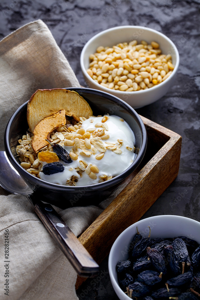 Healthy homemade breakfast is oatmeal granola with natural greek yogurt, nuts and raisins on dark gray background close-up.Dieting food concept.Vertical orientation Healthy homemade breakfast is oatmeal granola with natural greek yogurt, nuts and raisins on dark gray background close-up.Dieting food concept.Vertical orientation