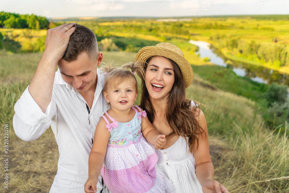 Happy family spending time together. Outdoors. Summer meadow. River on background Happy family spending time together. Outdoors. Summer meadow. River on background