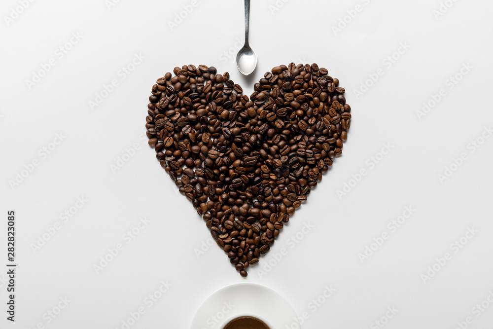 Φωτογραφία top view of coffee in cup on saucer with heart made of coffee grains near spoon