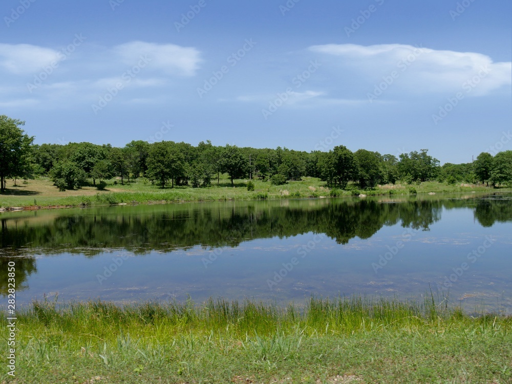 Wide lake view with trees mirrored in the lake waters at the Chickasaw National Recreation Area in Davis, Oklahoma