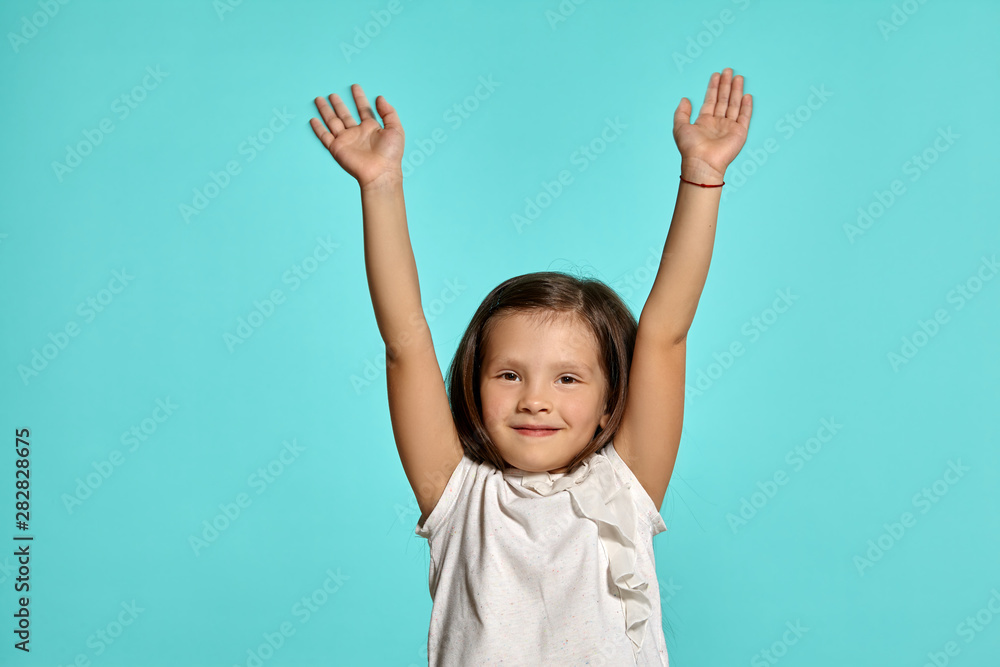 Close-up studio shot of beautiful brunette little girl posing against a blue background. Close-up studio shot of beautiful brunette little girl posing against a blue background.