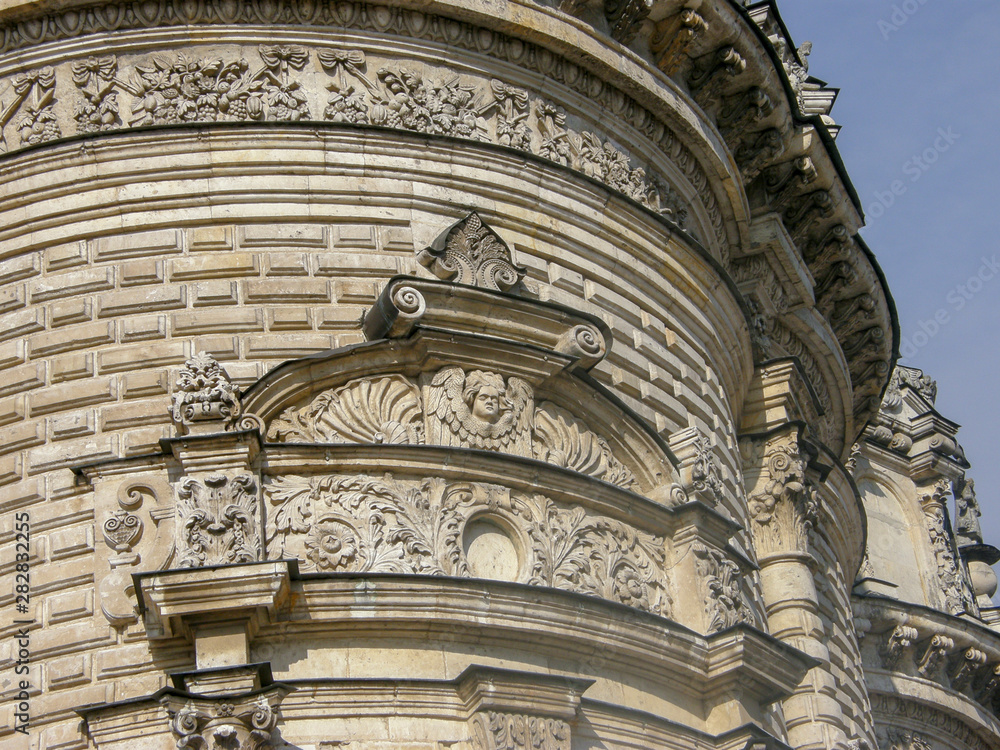 Stone carving on top of round tower on brick wall background