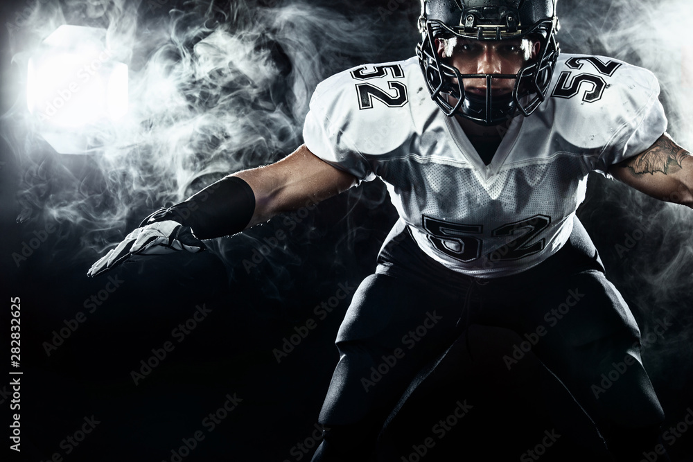 Fototapeta American football sportsman player in helmet on black background with smoke. Sport and motivation wallpaper.
