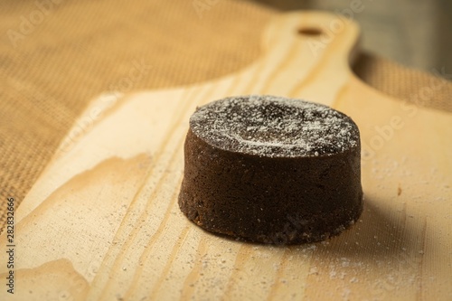 Chocolate fondant with icing sugars on top, on a black slate plate, selective focus