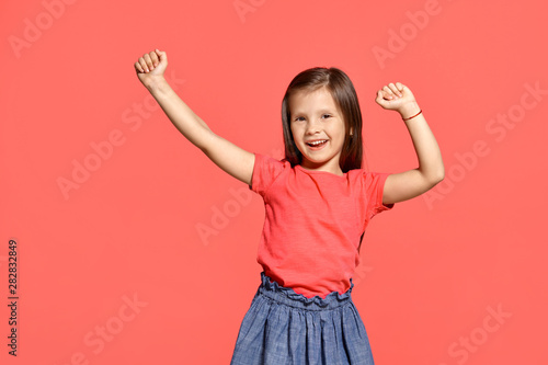 Close-up studio shot of beautiful brunette little girl posing against a pink background. photo