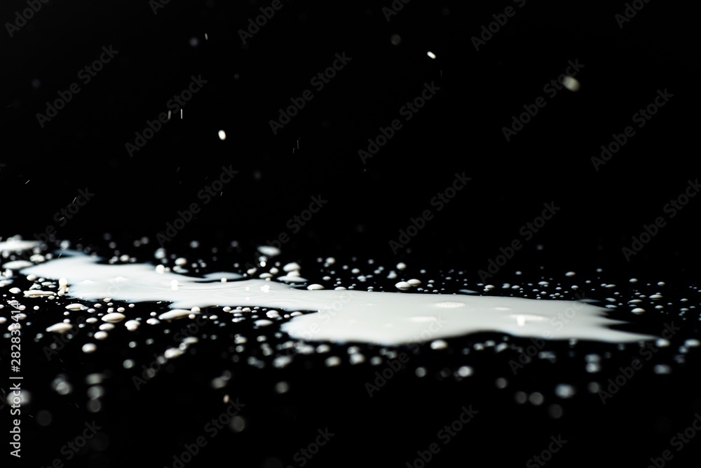 Milk spilled on black surface, closed up, selective focus Milk spilled on black surface, closed up, selective focus