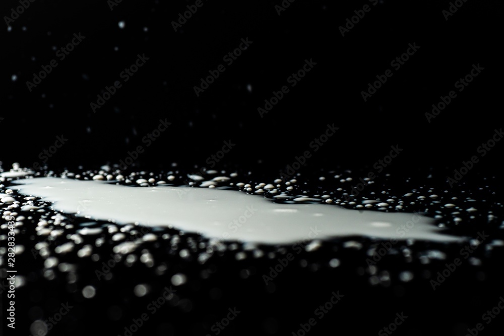 Milk spilled on black surface, closed up, selective focus Milk spilled on black surface, closed up, selective focus