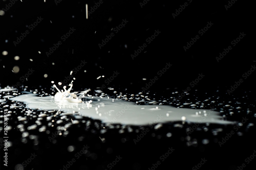 Milk spilled on black surface, closed up, selective focus Milk spilled on black surface, closed up, selective focus