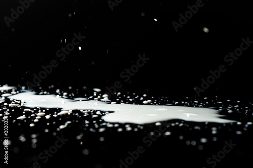 Milk spilled on black surface, closed up, selective focus