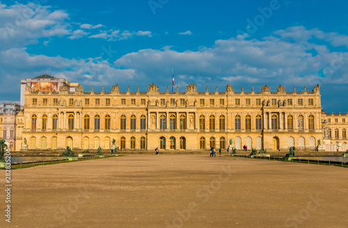 Perfect sunset panoramic view of the west facade of Versailles palace from the Water Parterre with two rectangular pools and a gravel path in the centre. The palace is a UNESCO World Heritage Site.