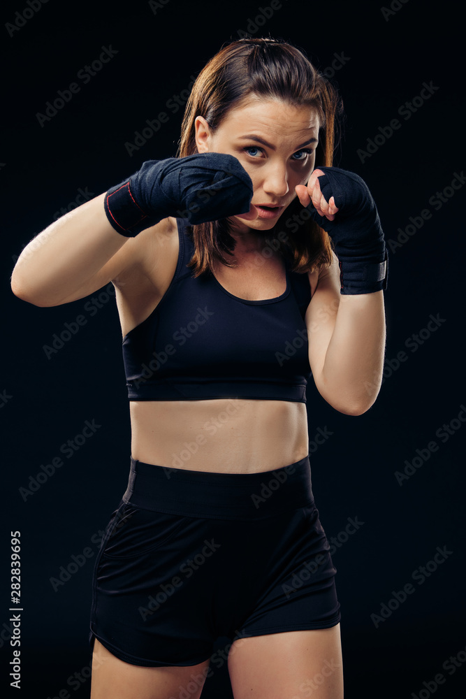 Athletic woman in boxing mittens is practicing karate in studio. Athletic woman in boxing mittens is practicing karate in studio.