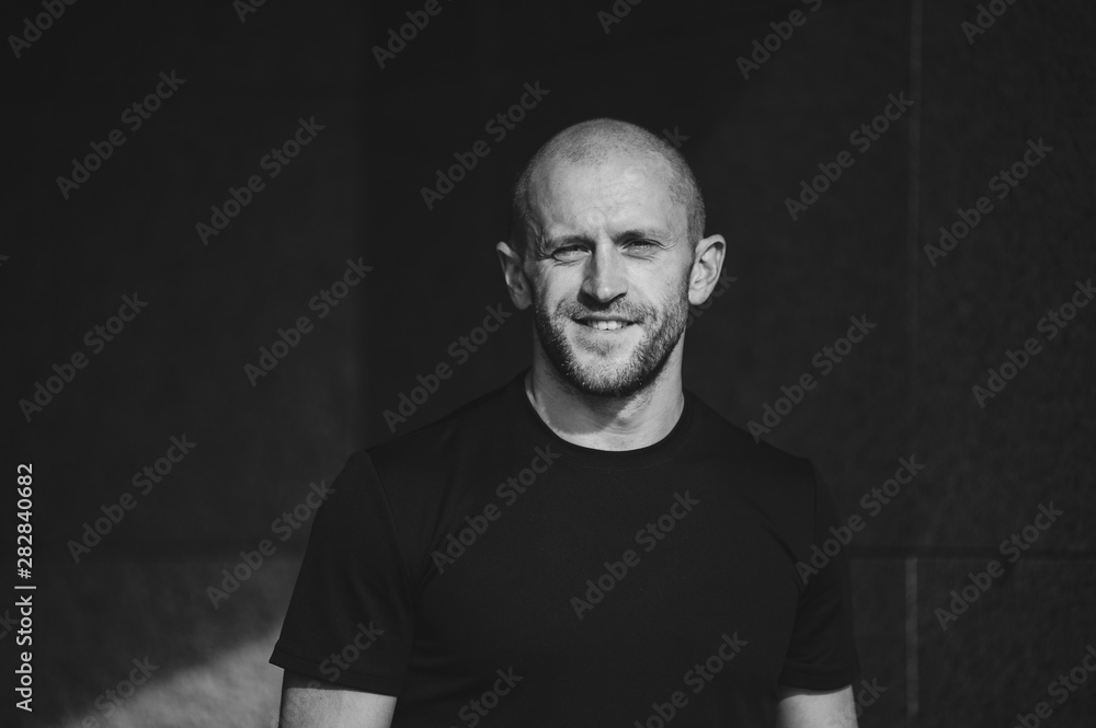 Fototapeta premium Horizontal portrait of young smiling man resting looking upwards in low key. Monochrome