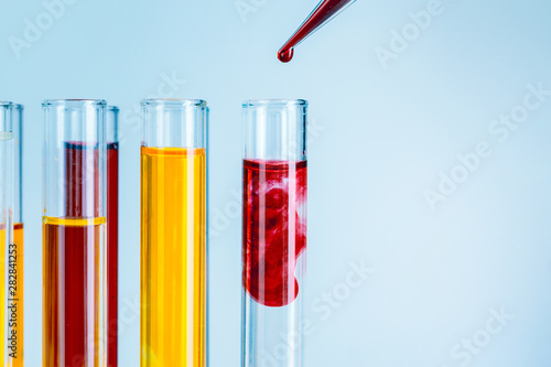 Laboratory test tubes with red and yellow liquids on light blue background