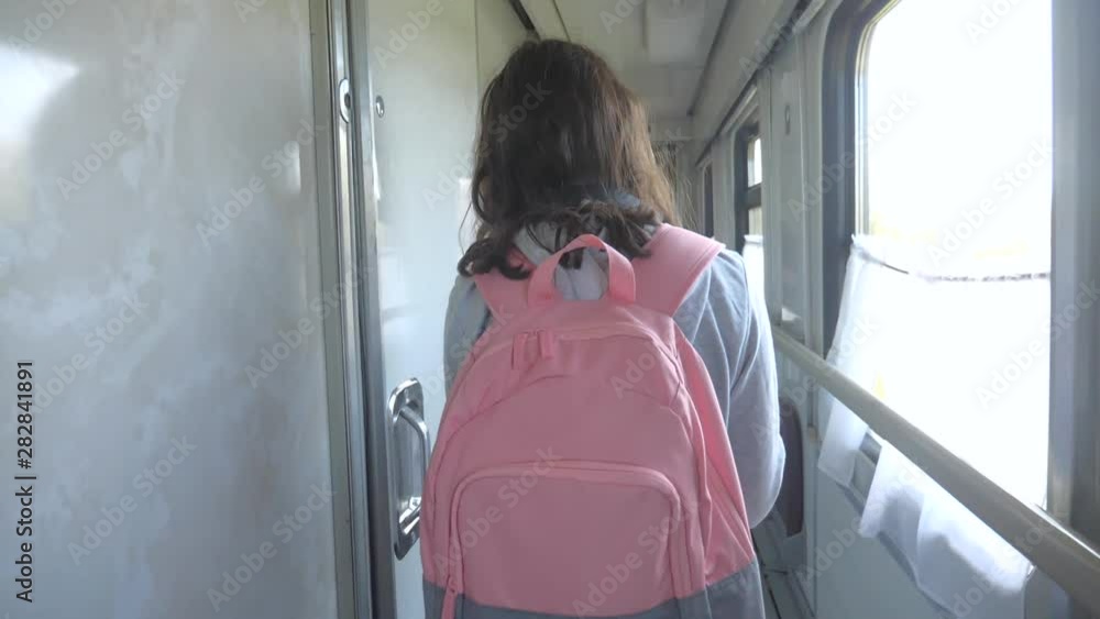 teen girl walks on a train compartment car with lifestyle a backpack . travel transportation railroad concept.little girl walking down the aisle of a train compartment car lifestyle the train wagon at teen girl walks on a train compartment car with lifestyle a backpack . travel transportation railroad concept.little girl walking down the aisle of a train compartment car lifestyle the train wagon at