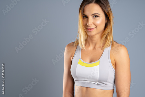 Portrait of a beautiful young sporty woman against gray background