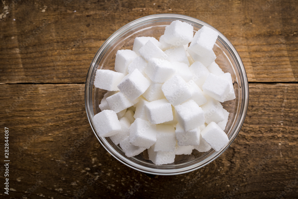 Closeup of sugar cubes in glass bowl on wooden table. Closeup of sugar cubes in glass bowl on wooden table.