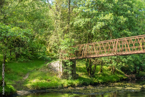 The upper reaches of the River Severn and a rusty iron bridge crossing in the Llanidloes countryside  Wales