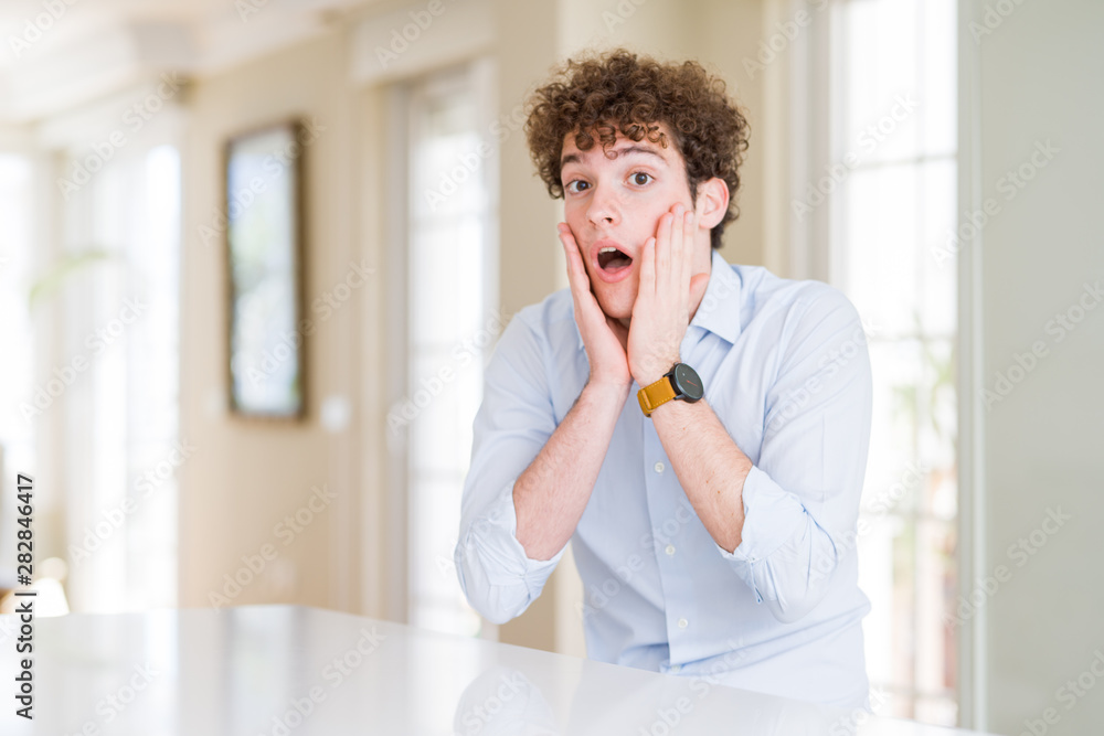 Young business man with curly read head afraid and shocked, surprise and amazed expression with hands on face Young business man with curly read head afraid and shocked, surprise and amazed expression with hands on face