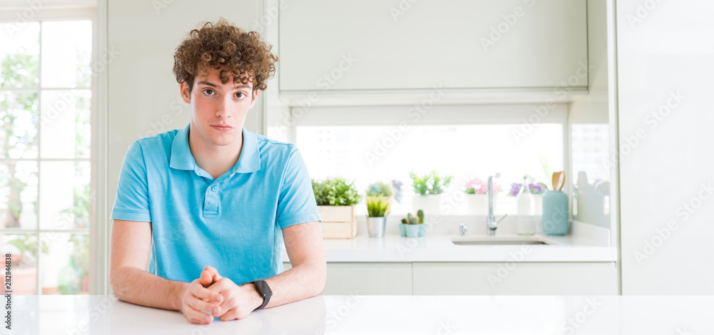 Wide shot of young handsome man at home depressed and worry for distress, crying angry and afraid. Sad expression.