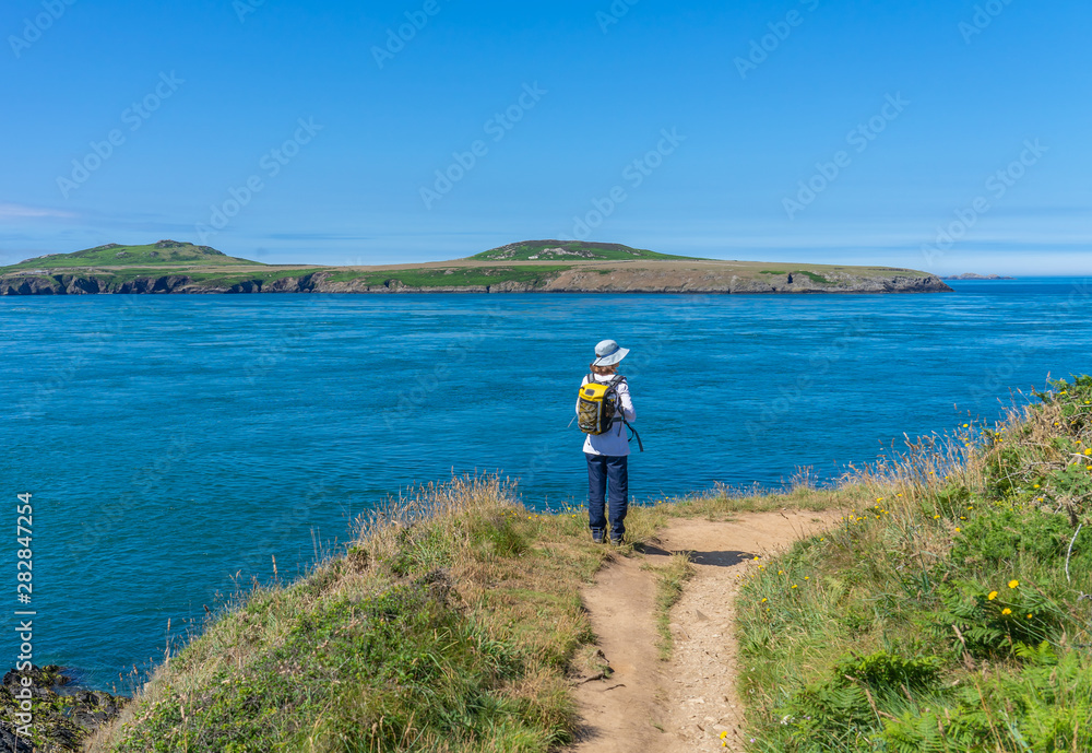 Lone adventurer standing on the cliff top in St Justinians looking out over Ramsey Sound towards Ramsey Island RSPB nature reserve