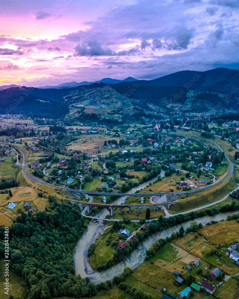 village in the mountains, old bridge viaduct, lilac sunset aerial view