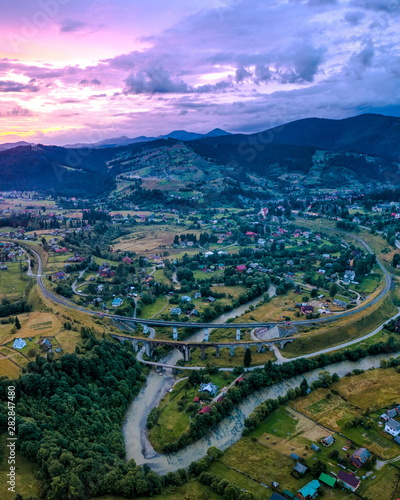 Obraz na płótnie village in the mountains, old bridge viaduct, lilac sunset aerial view w salonie