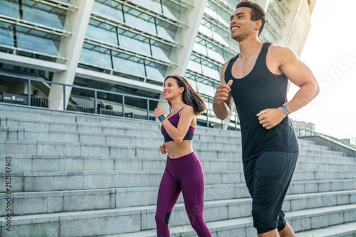 Young man and woman in jogging outfit running together outdoors © InsideCreativeHouse