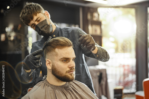 a guy doing a haircut and styling a beard 