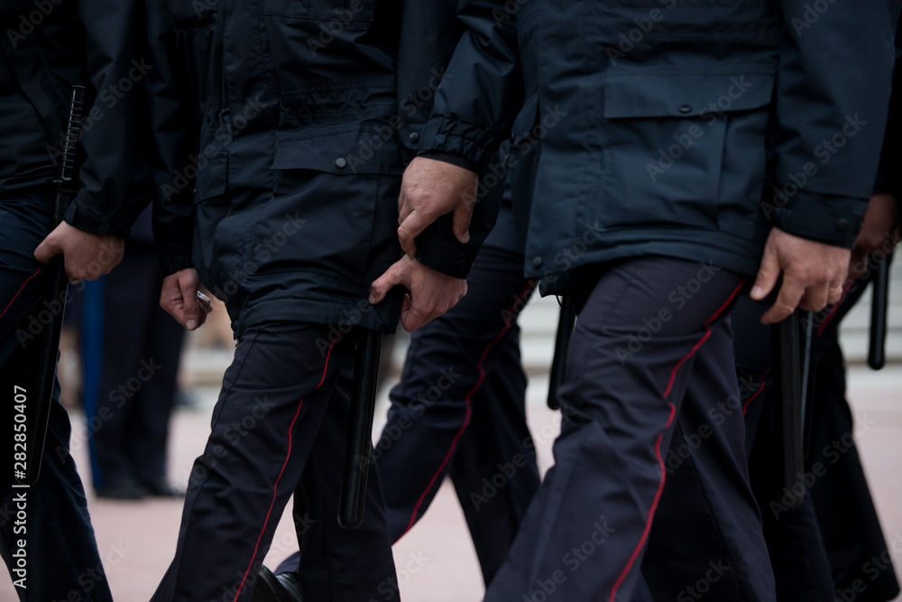 Russian police officers patrolling the street, rear view. Police officer holding a metal detector, security check. Russian police officers patrolling the street, rear view. Police officer holding a metal detector, security check.