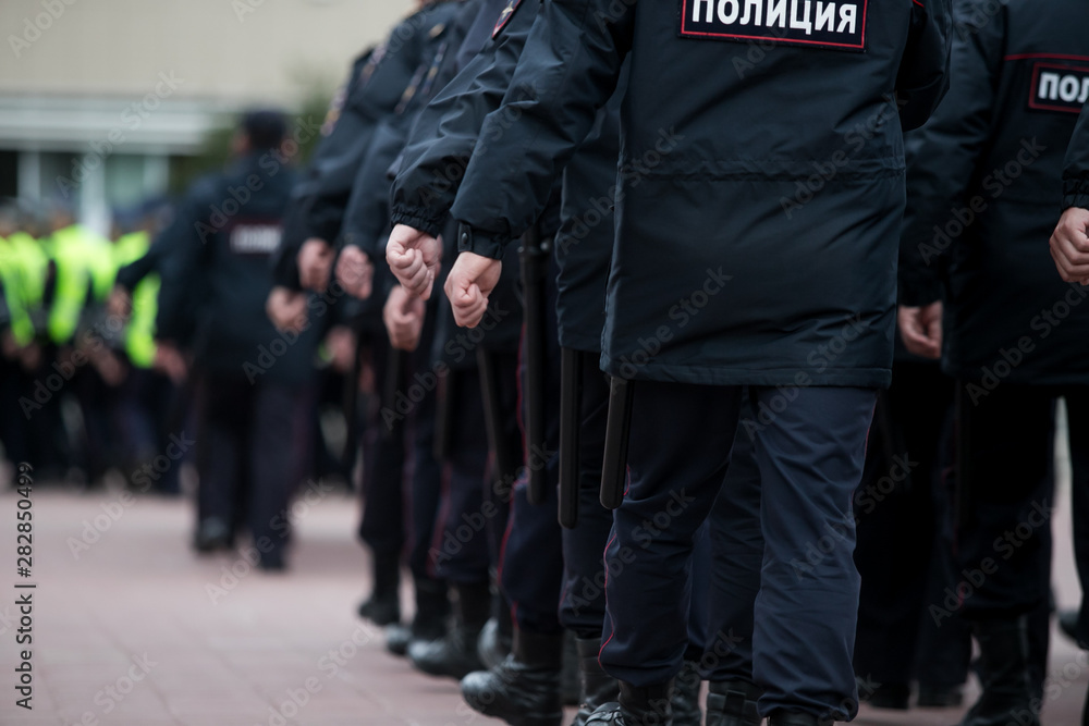 Russian police officers patrolling the street, rear view. Police officer holding a metal detector, security check. Russian police officers patrolling the street, rear view. Police officer holding a metal detector, security check.