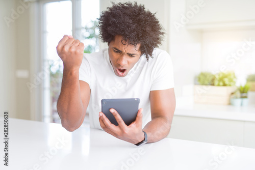 African American man using touchpad table annoyed and frustrated shouting with anger, crazy and yelling with raised hand, anger concept