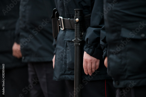 Russian police officers patrolling the street, rear view. Police officer holding a metal detector, security check.