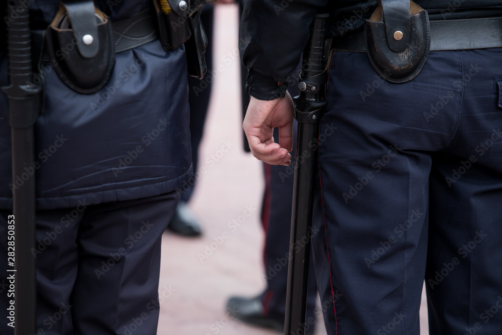 Russian police officers patrolling the street, rear view. Police officer holding a metal detector, security check. Russian police officers patrolling the street, rear view. Police officer holding a metal detector, security check.