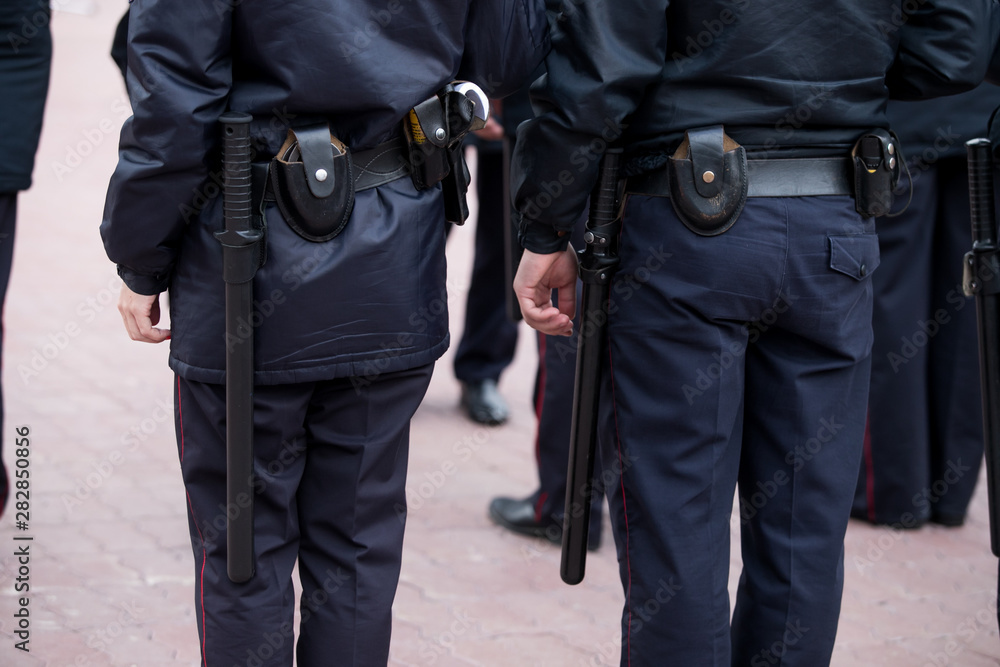 Russian police officers patrolling the street, rear view. Police officer holding a metal detector, security check. Russian police officers patrolling the street, rear view. Police officer holding a metal detector, security check.