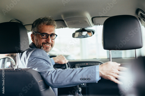senior businessman driving car looking at camera © cherryandbees