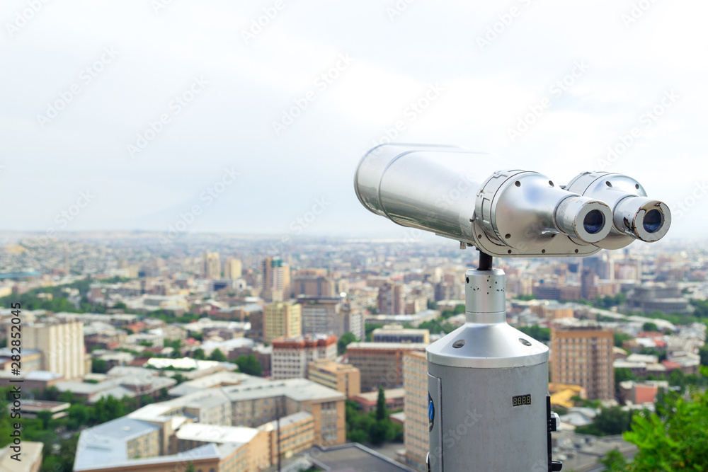 Tourist binoculars. View of the city landscape. Summer time. Travel concept