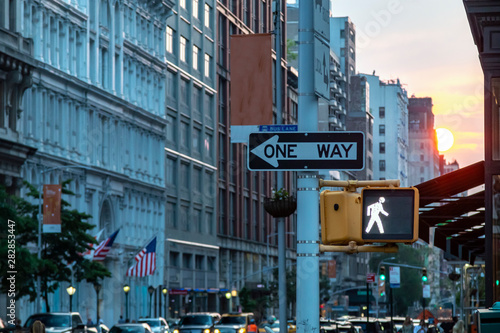 One way street sign on 5th Avenue in Midtown Manhattan New York City with the light of sunset in the background