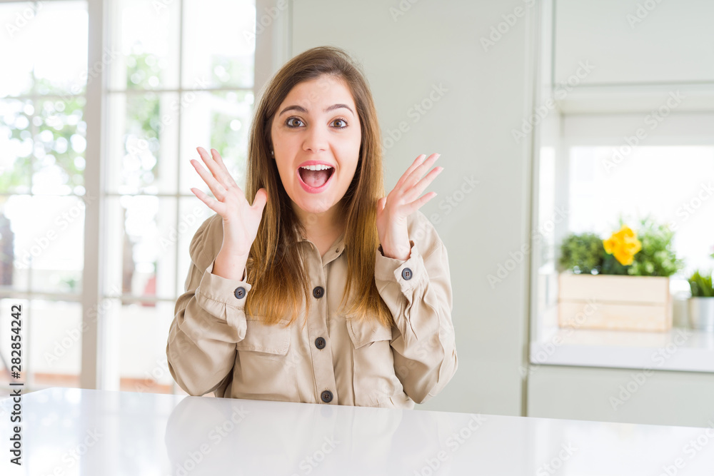 Beautiful young woman at home celebrating crazy and amazed for success with arms raised and open eyes screaming excited. Winner concept Beautiful young woman at home celebrating crazy and amazed for success with arms raised and open eyes screaming excited. Winner concept
