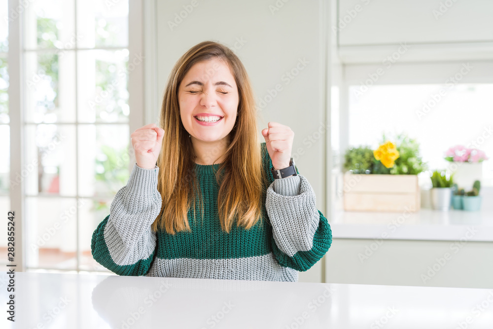 Young beautiful plus size woman wearing casual striped sweater excited for success with arms raised and eyes closed celebrating victory smiling. Winner concept. Young beautiful plus size woman wearing casual striped sweater excited for success with arms raised and eyes closed celebrating victory smiling. Winner concept.