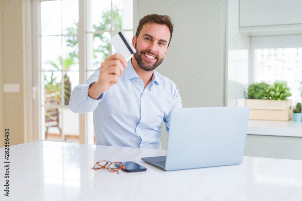 Handsome business man shopping online using computer laptop and credit card